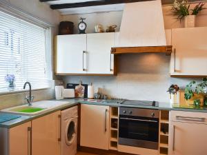 cocina con armarios blancos y lavavajillas en Meadowbank Lodge, en Staveley