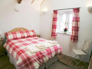 a bedroom with a bed and a window and a chair at Porth Nanven Barn in St Just