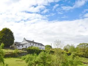 a white house on top of a hill with trees at Addyfield Farmhouse - 14512 in Bowland Bridge