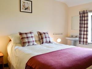 a bedroom with a bed with a purple blanket and a sink at Addyfield Farmhouse - 14512 in Bowland Bridge