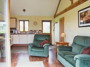a living room with two green couches and a kitchen at Bramble Cottage in Ripley