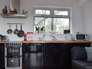 une cuisine avec un comptoir et une cuisinière ainsi qu'une fenêtre dans l'établissement Grooms Room, à Aberdare