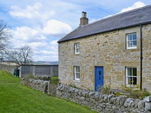 a stone house with a blue door and a stone wall at Rose Cottage in Rochester