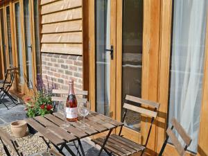 Fletching的住宿－霍利度假屋，庭院里的木桌和一瓶葡萄酒