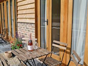 a wooden table with a bottle of wine on a patio at Holly in Fletching