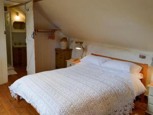1 dormitorio con 1 cama con edredón blanco en The Workshop - 27716, en Tipton Saint John