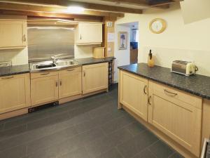 uma cozinha com armários de madeira e um lavatório em The Dairy em Dunvant