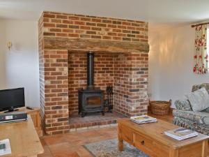 a living room with a brick fireplace with a stove at Copper Cottage in Burgh Saint Peter