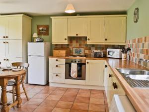 - une cuisine avec des appareils blancs et une table en bois dans l'établissement Copper Cottage, à Burgh Saint Peter