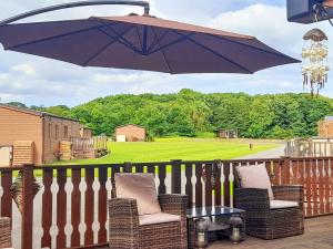 a porch with two chairs and an umbrella at Woodlands in Sewerby