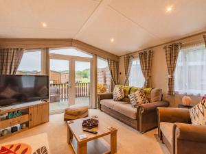 a living room with a couch and a flat screen tv at Woodlands in Sewerby