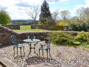a table and two chairs sitting next to a stone wall at Berrymoor Farm Cott in Kirkoswald