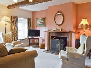 a living room with a fireplace and a tv at Berrymoor Farm Cott in Kirkoswald