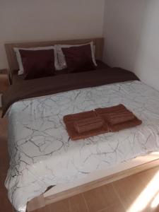 Una cama con sábanas blancas y toallas marrones. en Apartman KLM, en Pančevo