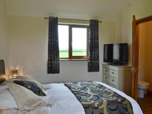 a bedroom with a bed and a tv and a window at Mill Stone Cottage - E5423 in Chapel Saint Leonards