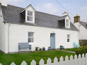 una casa blanca con un banco azul en el patio en Bydand Cottage, en Melness