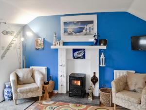 a living room with a fireplace and two chairs at Learig Cottage in Maidens