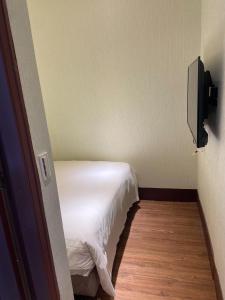 a small bedroom with a white bed and a television at 東南亞行旅 in Dajia