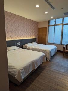 um quarto de hotel com duas camas e duas janelas em 東南亞行旅 em Ta-chia