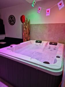 bañera grande con iluminación rosa en una habitación en Appartement - Spa en Monteux