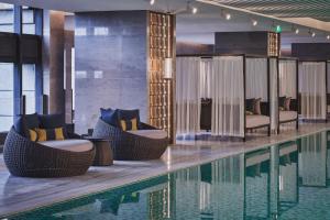 a pool with wicker chairs and chairs next to a swimming pool at HUALUXE Kunshan Huaqiao, an IHG Hotel - F1 Racing Preferred Hotel in Kunshan