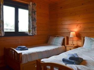 een slaapkamer met 2 bedden in een blokhut bij Churn - Uk12536 in Witheridge