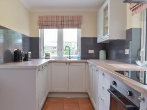 una cocina con armarios blancos y una ventana en Middleton Cottage en Llanddarog