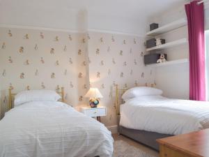 1 dormitorio con 2 camas y mesa en Middleton Cottage en Llanddarog