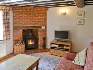 een woonkamer met een open haard en een televisie bij The Cottage in Great Ellingham