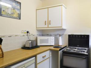 a kitchen with a counter with a stove and a microwave at Mallards in Wells next the Sea