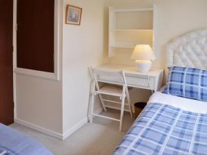a bedroom with a bed and a desk with a lamp at Mallards in Wells next the Sea