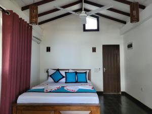 a bedroom with a large bed with blue pillows at Shima Guni Beach Club Hotel in Matara