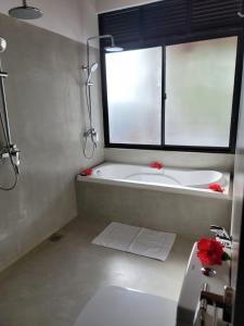 a bathroom with a tub and a sink and a window at Shima Guni Beach Club Hotel in Matara