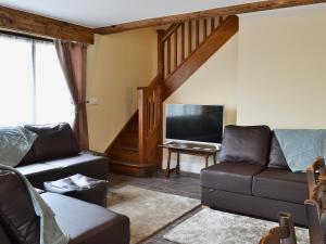 sala de estar con sofá y TV en Llaethdy-milkhouse, en Talgarth