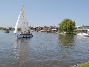 a boat with a sail in the water at Ripples in Horning
