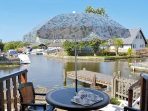 a table with an umbrella on a deck next to a river at Ripples in Horning