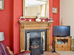 a living room with a fireplace and a mirror at Coble Cottage - 28317 in Flamborough