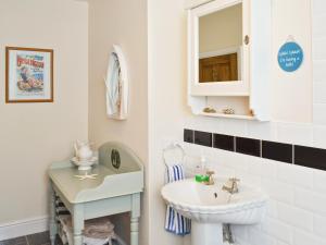a white bathroom with a sink and a mirror at Coble Cottage - 28317 in Flamborough