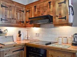 a kitchen with wooden cabinets and a stove top oven at Coble Cottage - 28317 in Flamborough