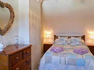 a bedroom with a bed with a dresser and a mirror at Coble Cottage - 28317 in Flamborough