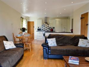 sala de estar con 2 sofás marrones y cocina en Watermill Cottage, en Hargrave