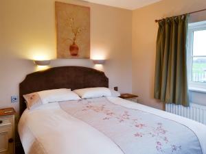 1 dormitorio con 1 cama grande y ventana grande en Watermill Cottage, en Hargrave