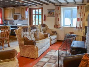 a living room with two couches and a kitchen at Haycombe Cottage in Camelford