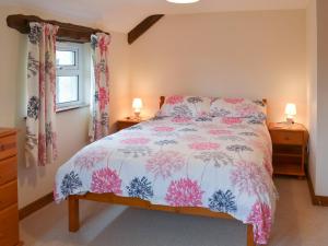 a bedroom with a bed with a pink and white comforter at Haycombe Cottage in Camelford