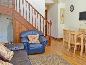 a living room with a blue leather chair and stairs at Rose Cottage - 30502 in West Firle