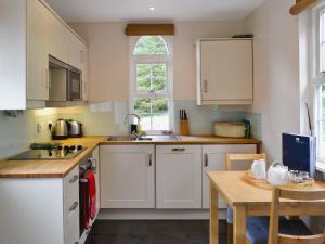 a kitchen with white cabinets and a wooden table at Jocky Milnes Croft in Haugh of Glass