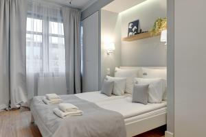 a white bedroom with a large bed with white pillows at Downtown Apartments Seaside Rezydencja Marina in Gdańsk
