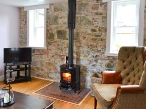 a fireplace in a living room with a brick wall at Roseburn Cottage in Moffat