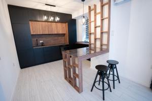een keuken met zwarte kasten en een aanrecht met krukken bij RCity Apartament 4 in Boekarest