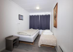 1 dormitorio pequeño con 2 camas y mesa en Kaikanten Rorbuer - Røst, en Røst